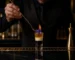 Bartender preparando un cóctel B-52 flameado por capas