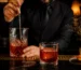 Bartender removiendo un cóctel Negroni en una barra oscura